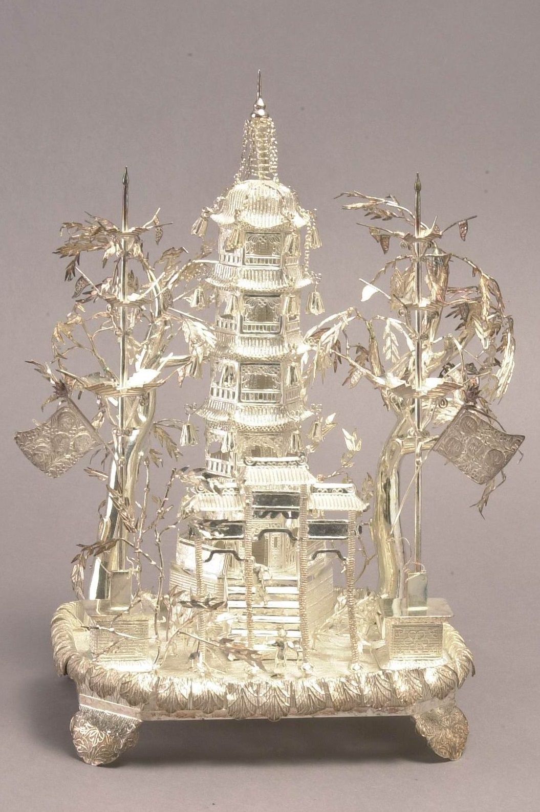 Silver ornament featuring trees and a pagoda.